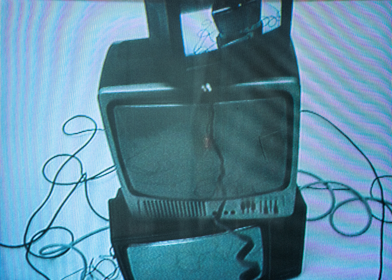 Stacked CRT televisions rephotographed from a screen, cables coiled around them
